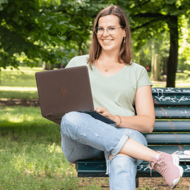 Olga Weiss sitzt mit Laptop auf einer Parkbank